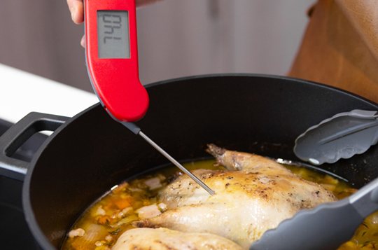 A red digital handheld Thermapen thermometer being used to take the internal temperature of a pheasant