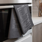 Grey tea towel with temperature guide hanging on a kitchen oven.