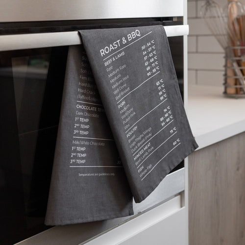 Grey tea towel with temperature guide hanging on a kitchen oven.