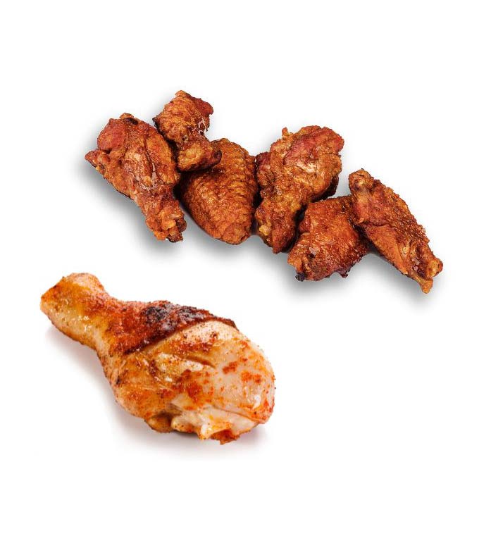 A cooked chicken leg, seasoned with paprika and spices, is positioned in the foreground of a white background. In the background, five chicken wings, also cooked and seasoned, are arranged in a group.