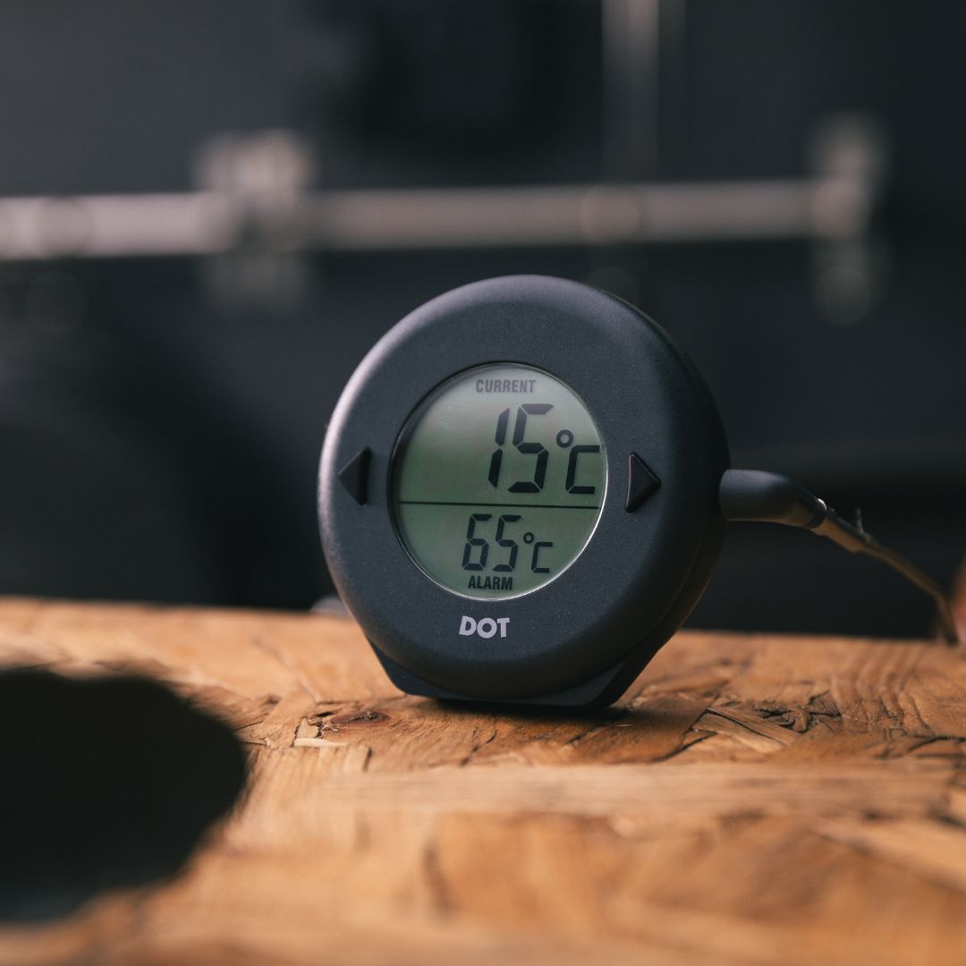 A charcoal DOT thermometer on a wooden surface