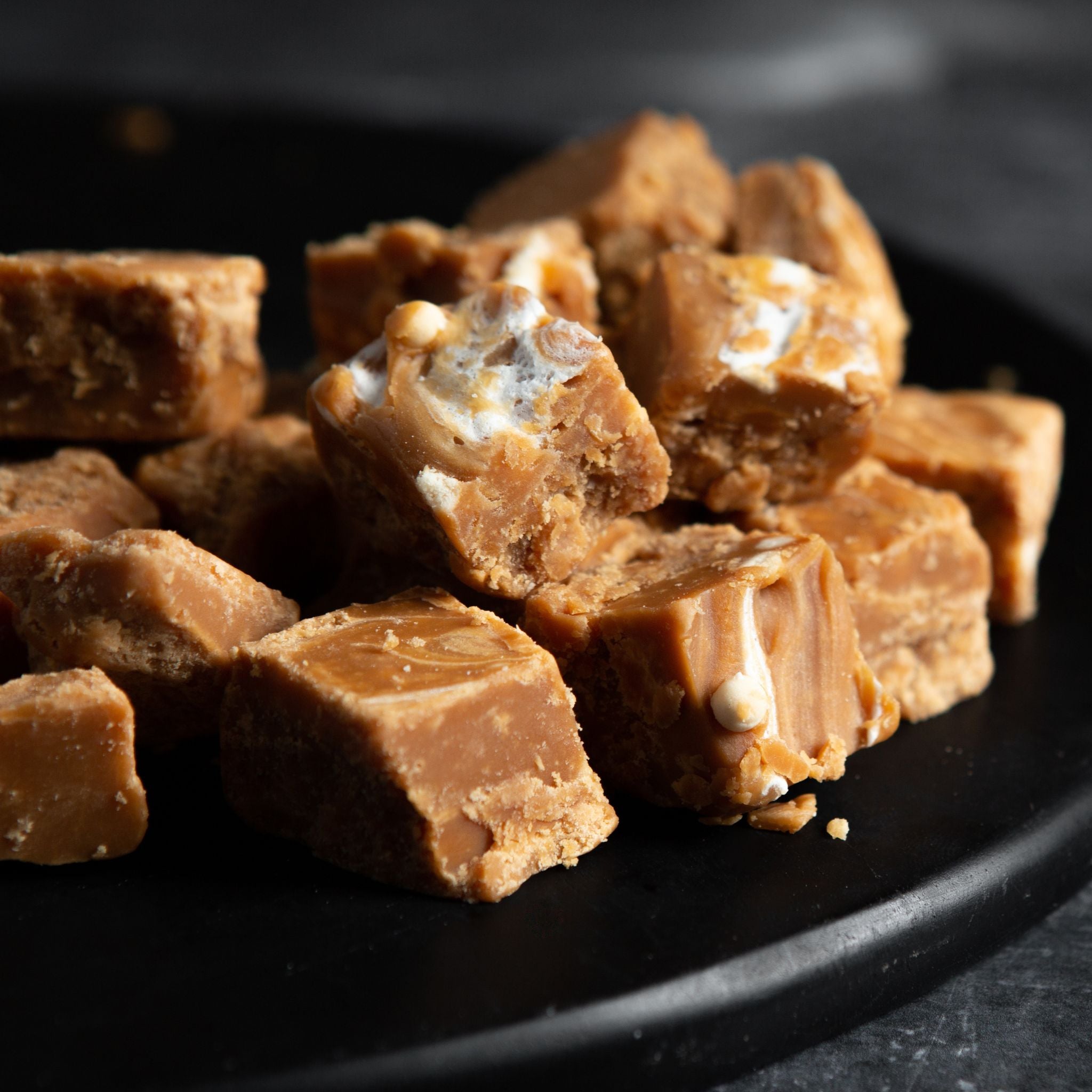 Fudge piled on black plate on a dark background