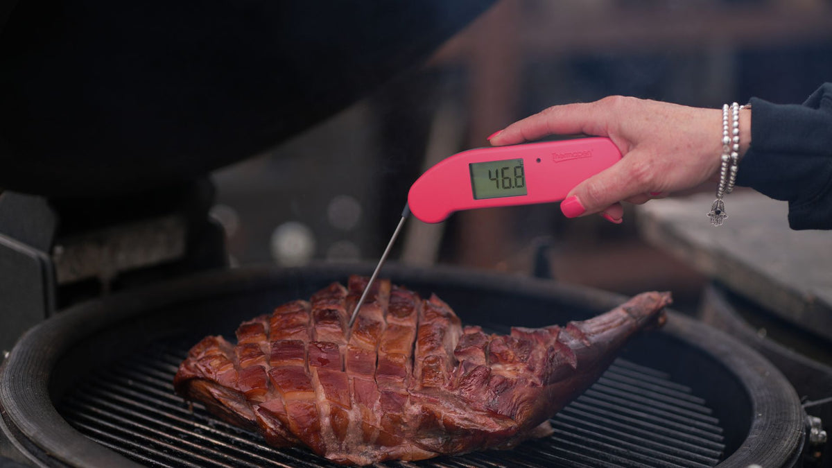 Thermapen ONE raspberry measuring the temperature of Lamb leg on a BBQ