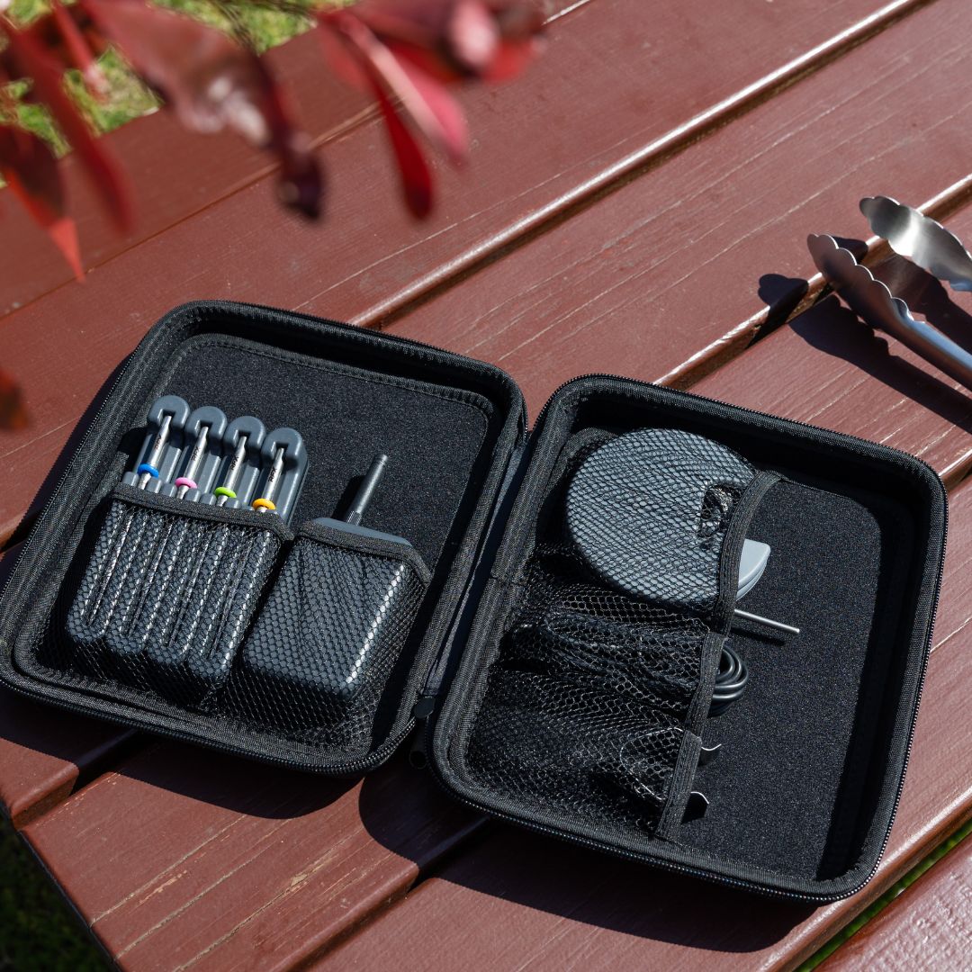 open black case on a wooden bench showing four RFX probes in charging docks, gateway, probe spool, cable and grate clip, with tongs in the background