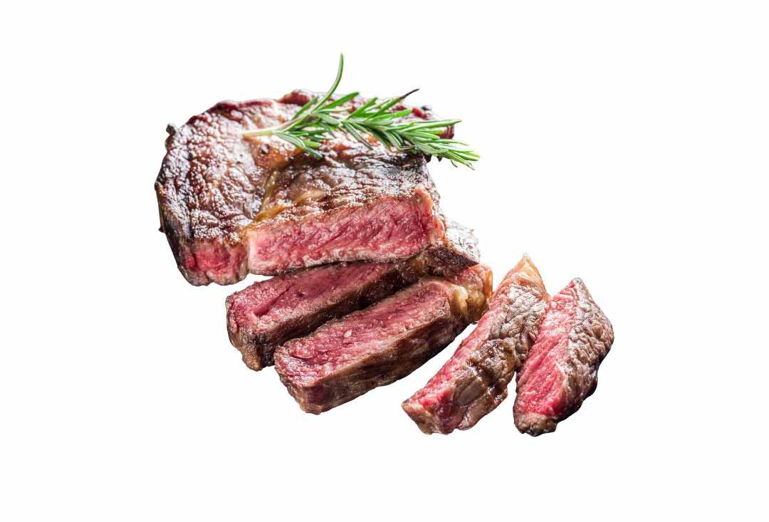 A thick, juicy steak cooked rare, with a seared brown crust and a vibrant red, tender interior. Several slices are fanned out from the main piece, and a sprig of fresh rosemary garnishes the top of the steak, all presented on a clean white background