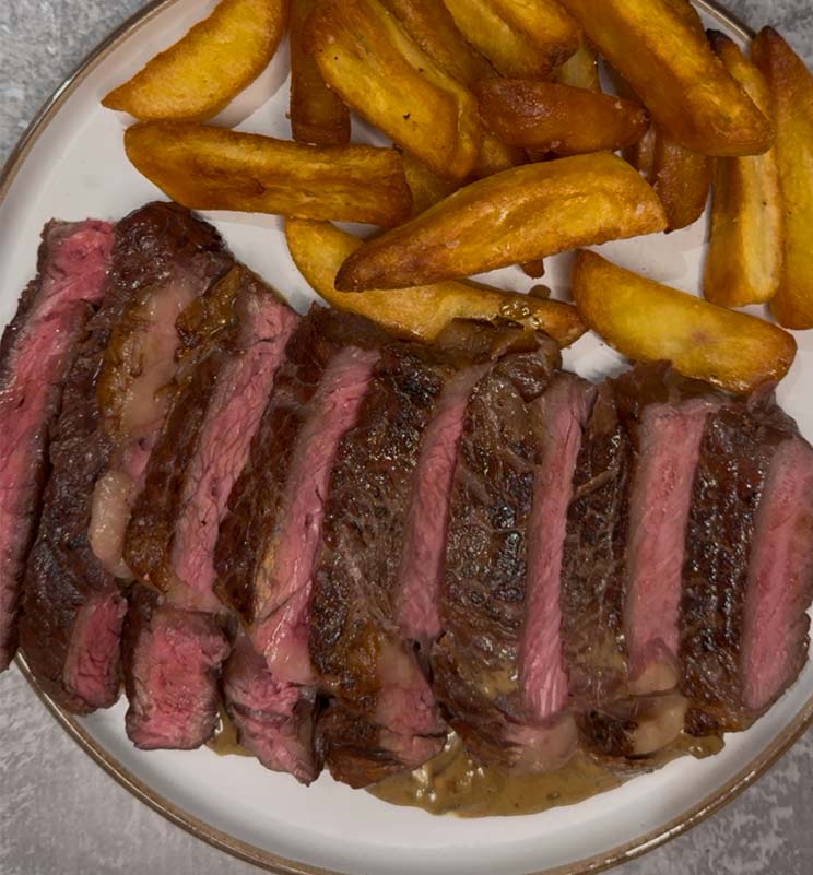 finished ribeye steak with sauce and chips