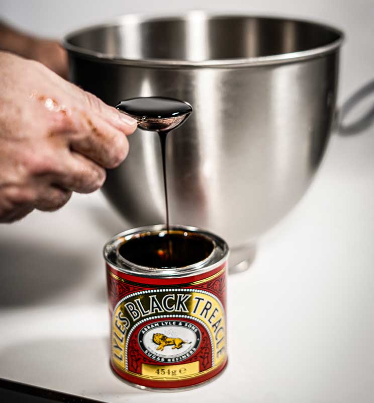 Close up view of treacle on a spoon dripping down into the can