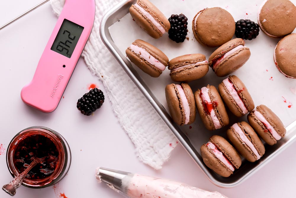 Macarons, blackberries and jam on a white table