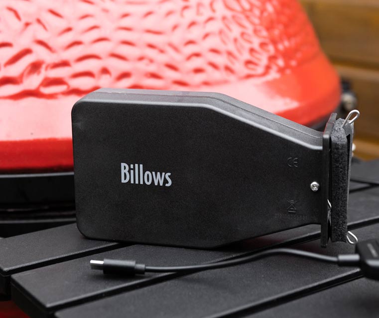 Billows BBQ fan with it's logo visible, positioned next to a Kamado styled BBQ with it's USB adapter next to it