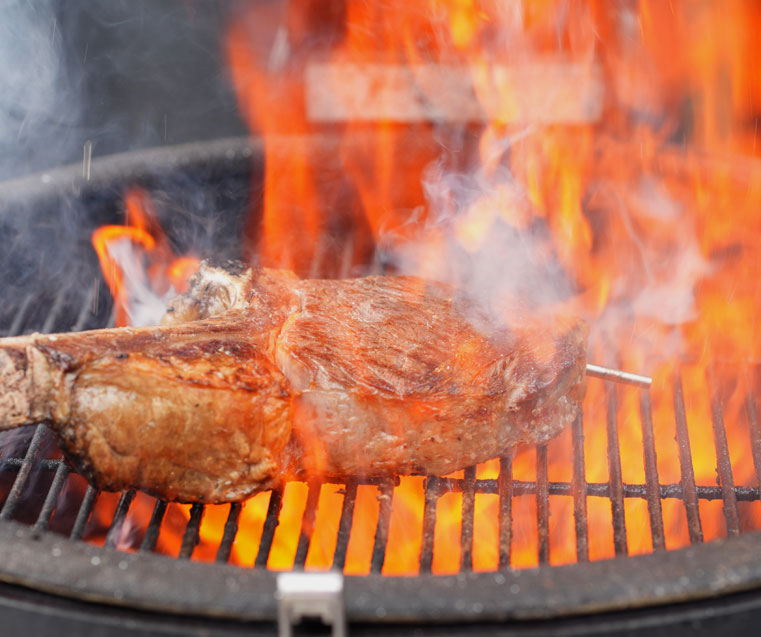 Tomahawk on the BBQ with RFX meat probe visible and flames flying high all over the meat, RFX and the BBQ