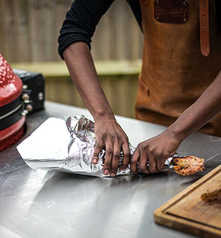Chef wrapping leg of lamb in foil