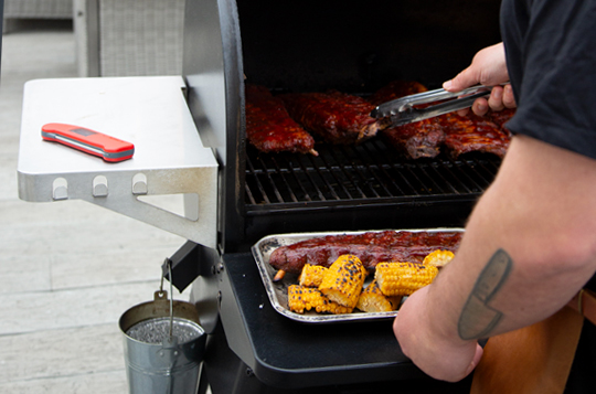 Ribs that have reached temperature using a Thermapen being taken off the BBQ by a man