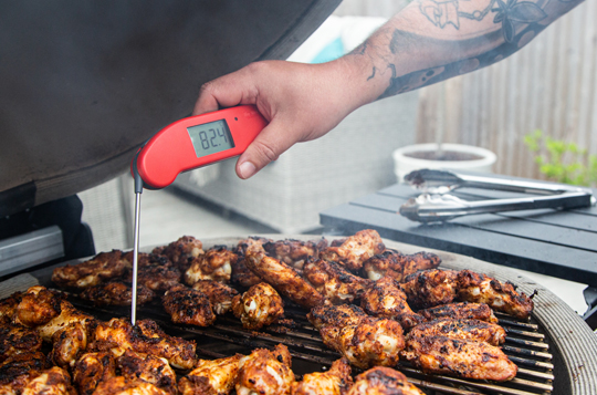 Red Thermapen, digital thermometer being used to take the internal temperature of chicken