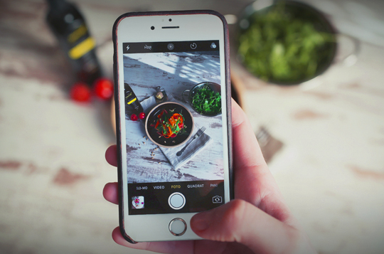 A white Iphone being used to take an image of a bowl of food