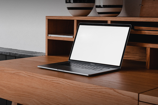 A laptop sat on a wooden table in someones home 