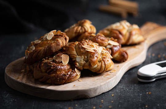 Cinnamon buns presented on a wooden chopping board next to a white, Thermapen, food thermometer