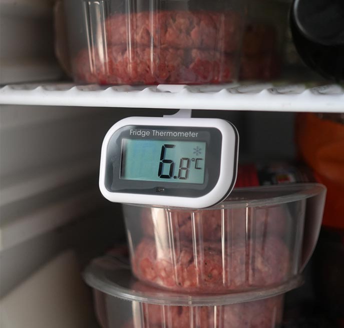 Frdige Thermometer shoing the temperature hanging from a fridhe shelf with minced meat boxes in the backround