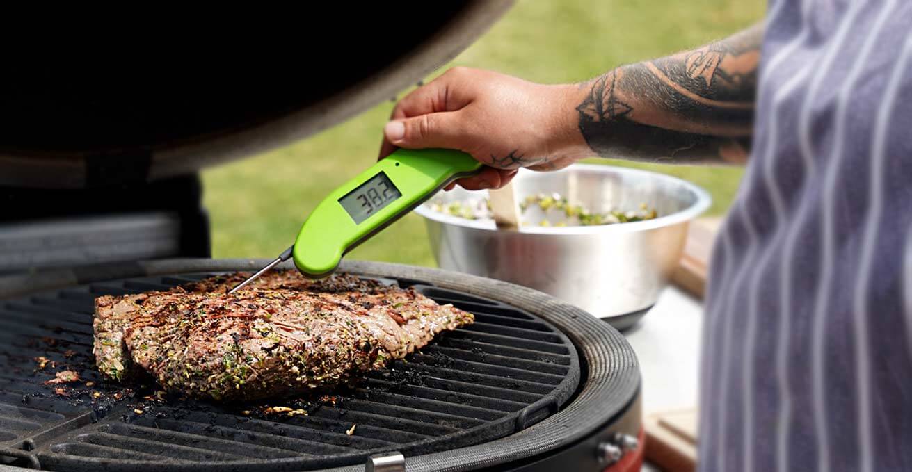 summer bbq with the green Thermapen ONE taking the temperature of steak on Kamado Joe bbq