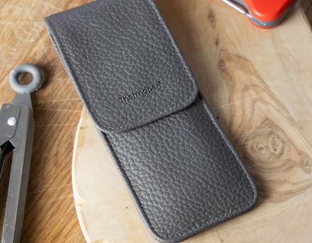 This image is a close-up of a protective carrying case for a Thermapen thermometer, laying on a wooden chopping board.