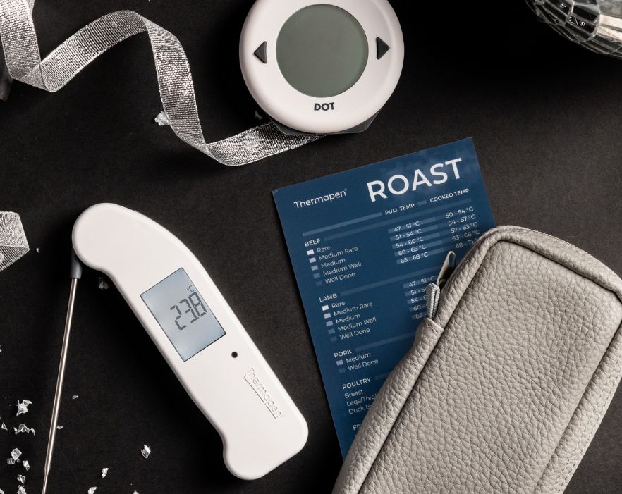 This image features several Thermapen brand cooking thermometers and accessories arranged on a dark, festive background with silver tinsel.