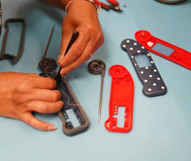 Hands cleaning Thermapen Probe at a work station with Thermapen Calibration Certificares on the table with the product boxes near by.