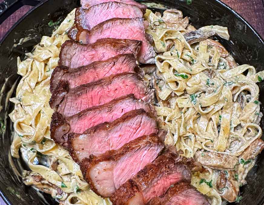 Steak Alfredo Pasta close up on a black plate