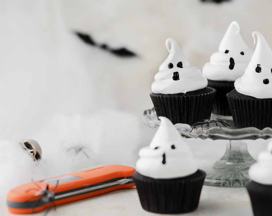 Halloween meringue ghost cupcakes with orange Thermapen ONE and tiny spiders as decorations around it