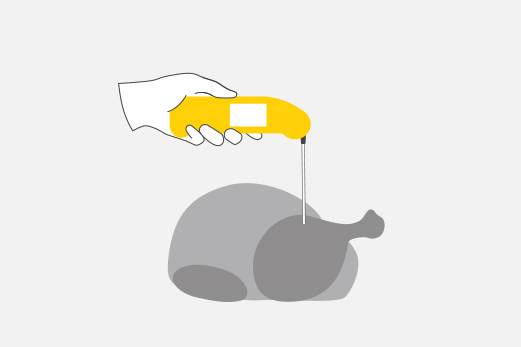 A hand holds a Thermapen, inserting the probe into a whole chicken to take an internal temperature reading for doneness.