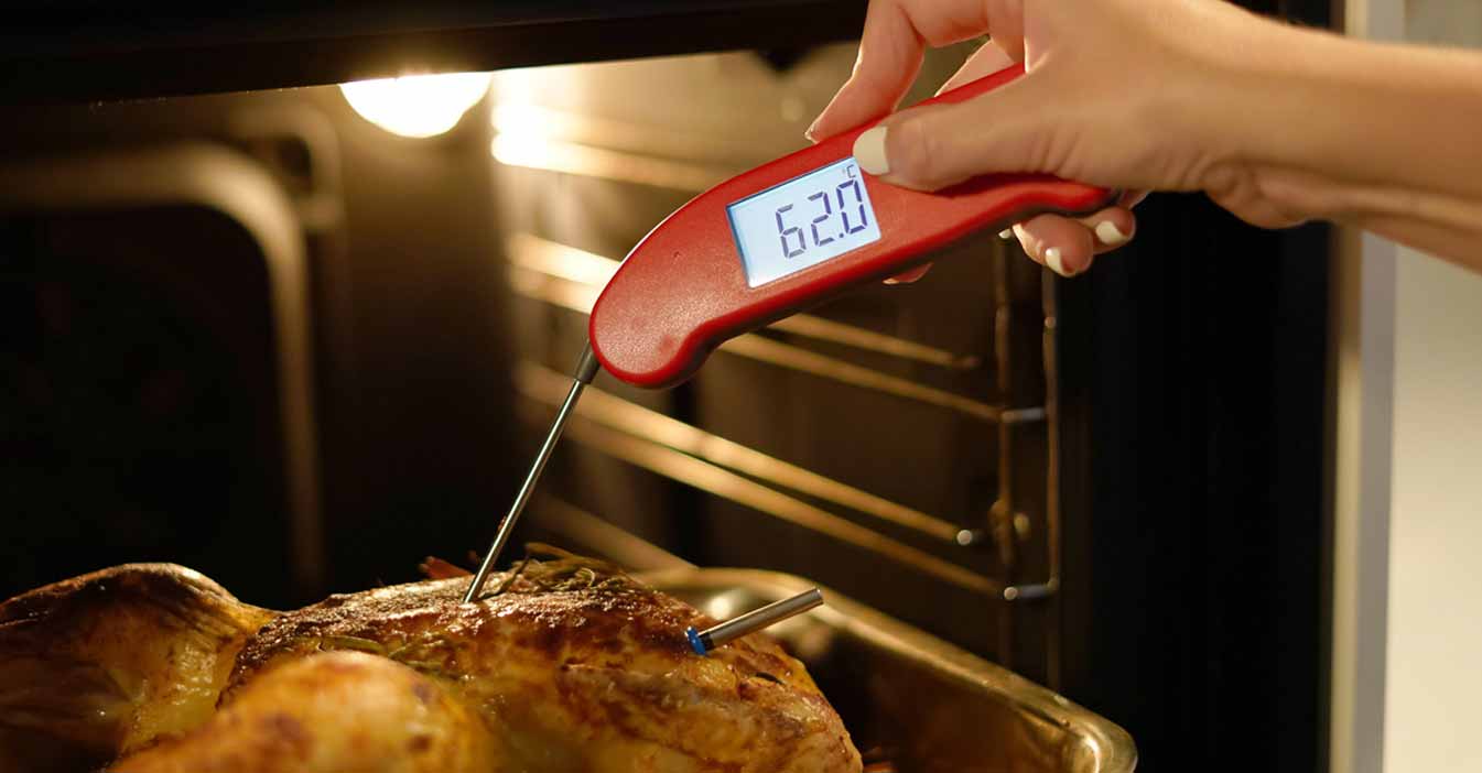 A red Thermapen ONE is used to measure the temperature of roast chicken in the oven, RFX Meat probe also visible in the thickest part of the chicken